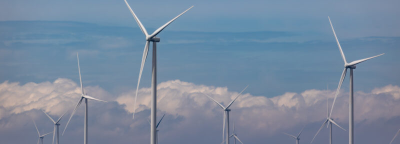 Large wind turbines stand in the ocean. 